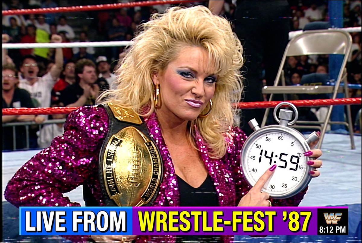 Vixen Vance holding up a giant stopwatch, unbothered, at ringside