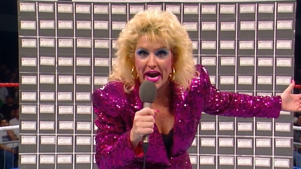 Vixen Vance in a magenta sequined jacket at ringside, microphone raised, mid-promo
