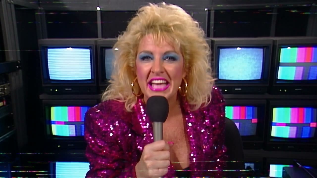 Vixen Vance in a magenta sequined jacket in a 1987 outside-broadcast truck, microphone in hand, in front of a wall of CRT monitors